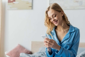 Девушка читает сообщение на телефоне и улыбается