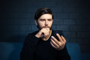 Парень решительно блокирует контакт в телефоне