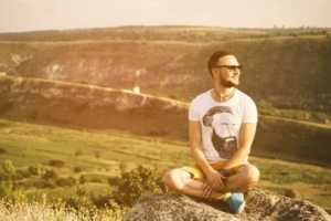 Мужчина сидит в позе медитации на природе на рассвете